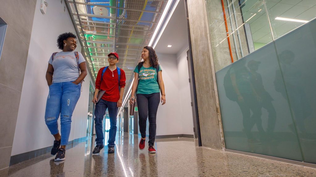 three students walking in the hallway